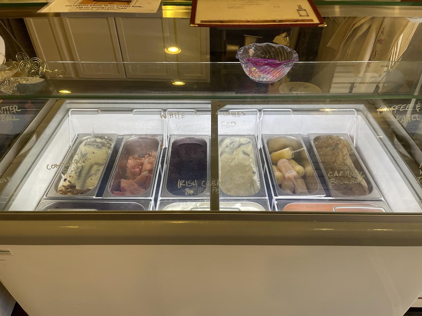 Tubs of ice cream in a lit glass case at Magnolia Market, with hand written labels on the glass and an ID sign above it.